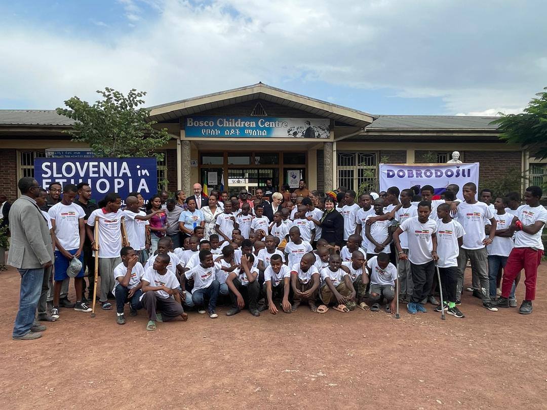 Morda je slika naslednjega: 3 osebe in besedilo, ki pravi »Children ChildrenCentre Centre የመስኮልጆችማለከል የቦስኮ ልደች ማዕከል SLOVENIA in ΕΤΨ باز 4e e 生イ元屋 DOBRODOŚLI T«